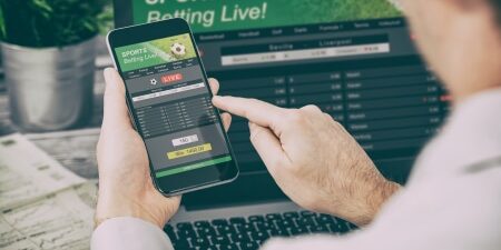 How-to-deal-with-gambling-debt-feature person placing a bet online on smartphone