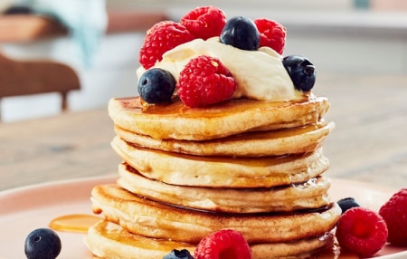 stack of pancakes topped with blueberries and raspberries