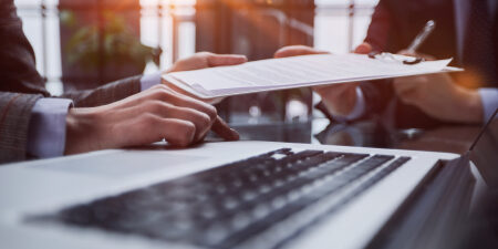 close up of clipboard being handed from one pair of hands to another