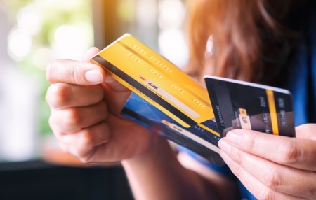 Image of someone holding yellow and blue credit cards.