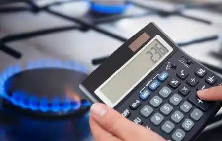 Image of a calculator being held close to a gas hob