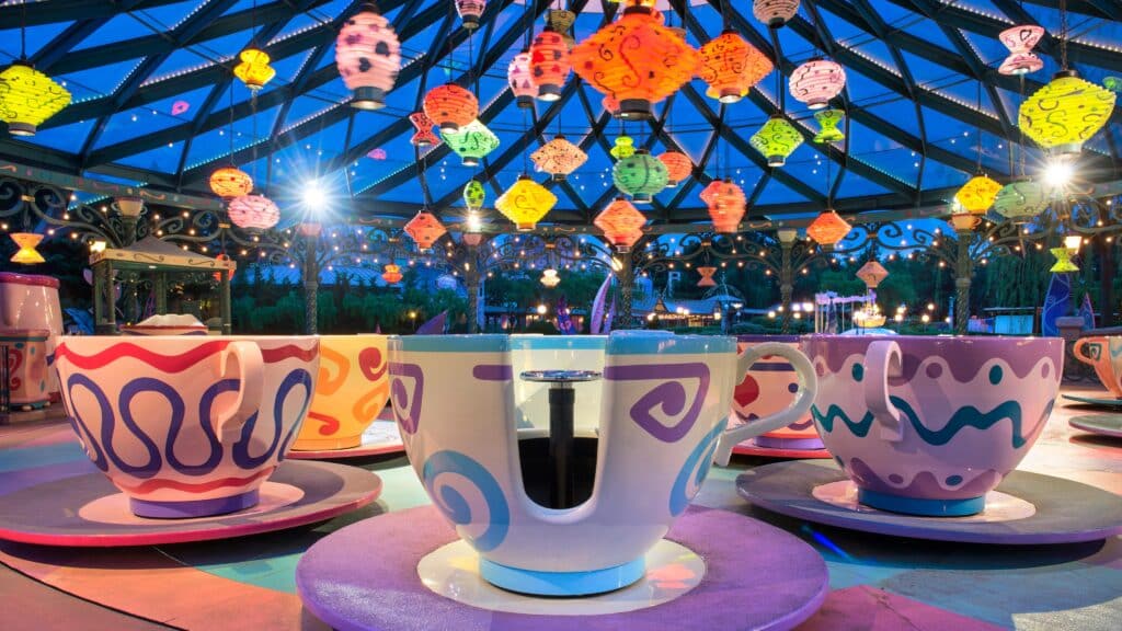 Image of colourful teacup rides at a theme park under the night sky.