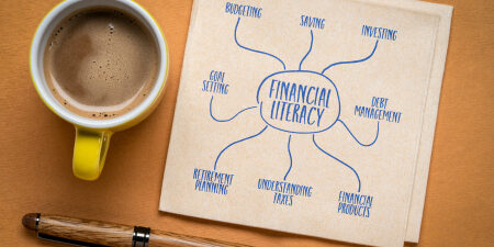 What-Is-Financial-Literacy_-feature An image of 'financial literacy' on a piece of paper next to a pen and a coffee