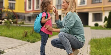 Are-You-Eligible-for-Additional-Childcare-Support-feature Women with her child smiling outside of a block of flats