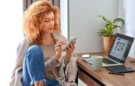 A woman sat at her desk looking on her phone.