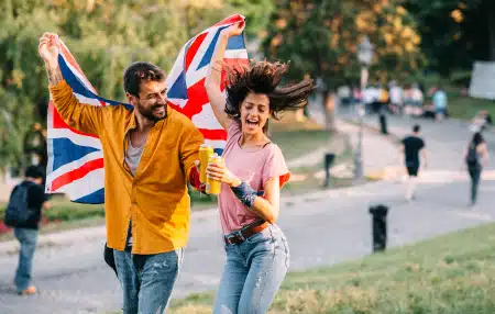 An image of a man and a woman waving a Union Jack flag in a festival park