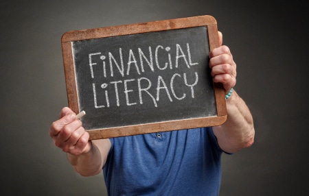 An image of a man holding up a mini black board with the writing 'Financial Literacy'