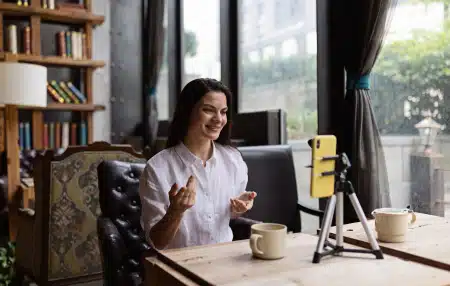 An image of a woman sitting at her desk filming content for social media.