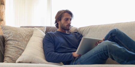 What-are-the-5-Principles-of-Financial-Literacy-feature Image of man laying on the sofa looking at his iPad