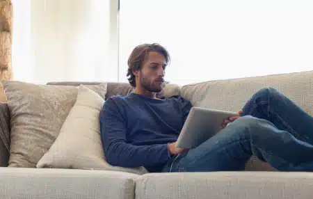 Image of man laying on the sofa looking at his iPad 