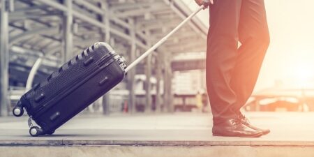 Can-I-move-abroad-with-debt-feature An image of a man pulling a suitcase towards the airport.