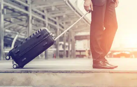 An image of a man pulling a suitcase towards the airport.