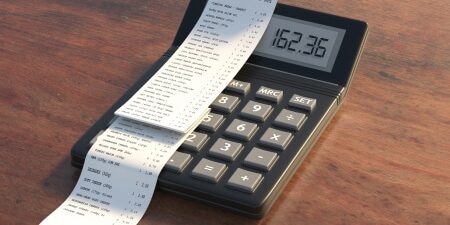 How-to-Deal-with-Unexpected-Expenses-feature Image of a calculator on a wooden desk with a receipt on top