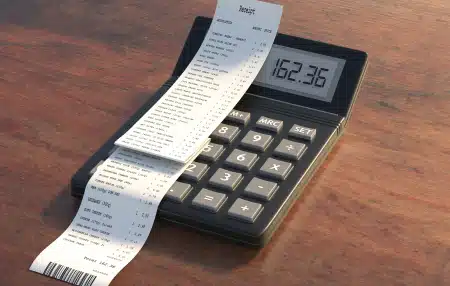 Image of a calculator on a wooden desk with a receipt on top 