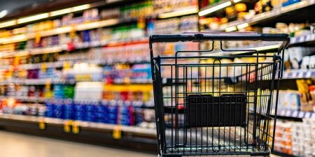 How-to-Save-Money-on-the-Weekly-Shop-feature Image of a shopping trolley in an aisle at a supermarket