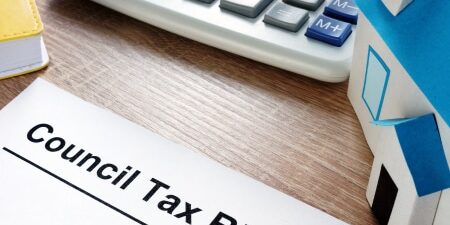 Image of a computer keyboard on a wooden desk with a council tax bill letter.