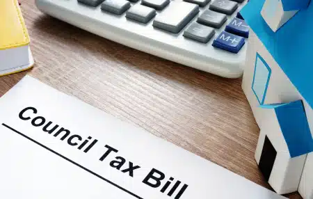 Image of a computer keyboard on a wooden desk with a council tax bill letter.