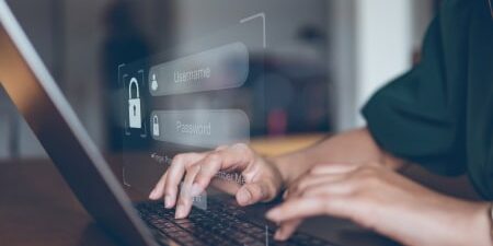 What-Is-Identity-Theft-feature-1 Image of someone typing on their laptop with the screen requesting their username and password.