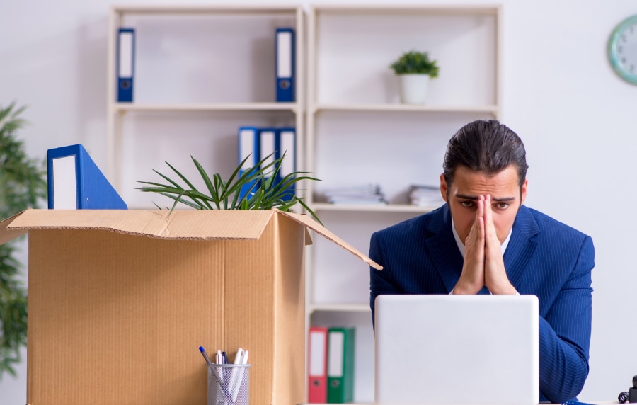 An image of a man sat at his desk with his head in his hands.