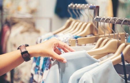 Image of someone searching through a clothes rack in a shop