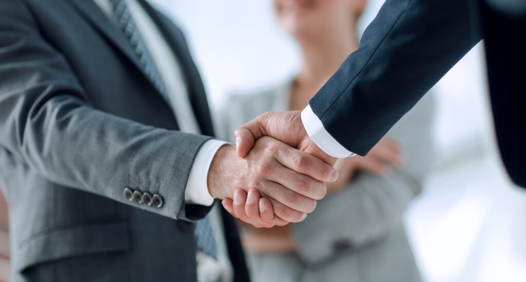 Closeup of handshake of business partners on the background of business team