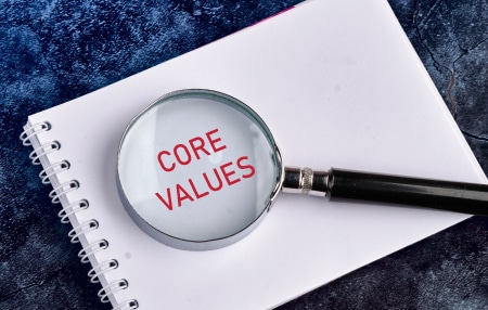 Image of a notepad with the words "core values" and a magnifying glass on top