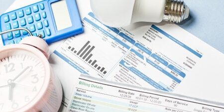 What happens if you can’t pay your energy bills feature Image of bills, a light bulb, an alarm clock and a calculator