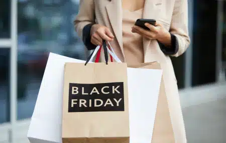 Image of a woman holding a few Black Friday shopping bags.