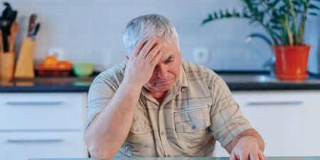 Good Debt vs Bad Debt_ What You Need To Know feature Image of a man with his head in his hands, sat at his table looking at a letter.