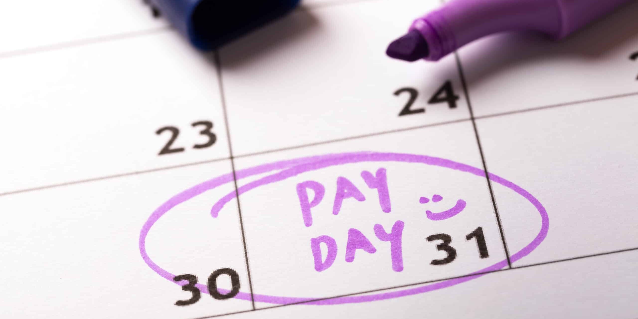 payday concept calendar with marker and circled day of salary Calendar with "Pay Day" written on the 31st, highlighted in purple marker.