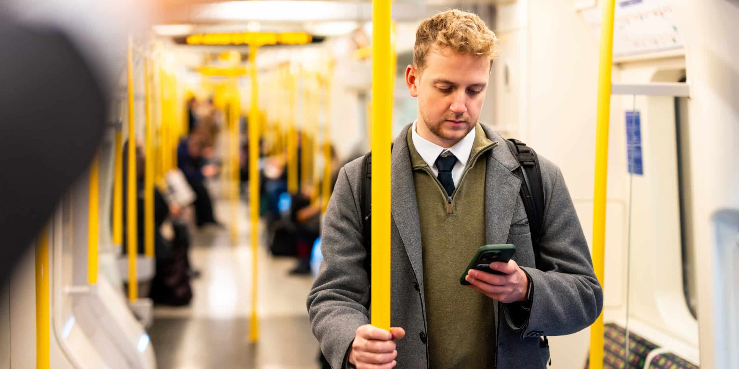 Businessman using smartphone while standing on subway train
