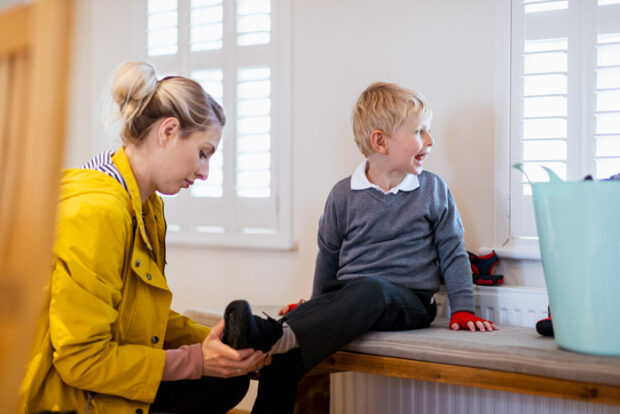 child-shoes A wide shot of a Caucasian, mother helping her son put his shoes on before school.